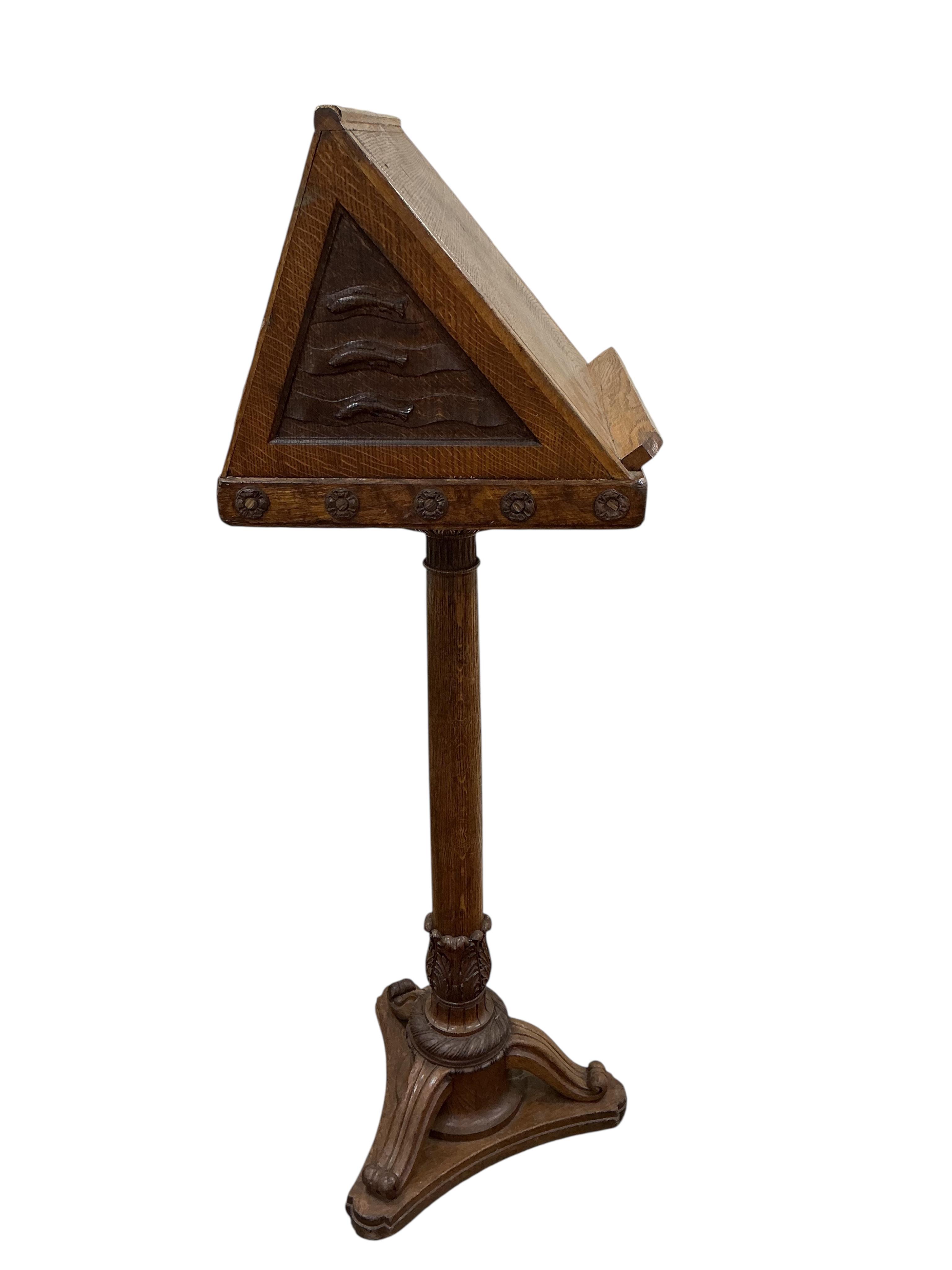 A mid 20th century oak lectern carved with ribbon fold floral swag and the legend “Rolfe George Martin, M.A (Cantab), First Headmaster of The School, 1924 - 1947. Height 142cm.